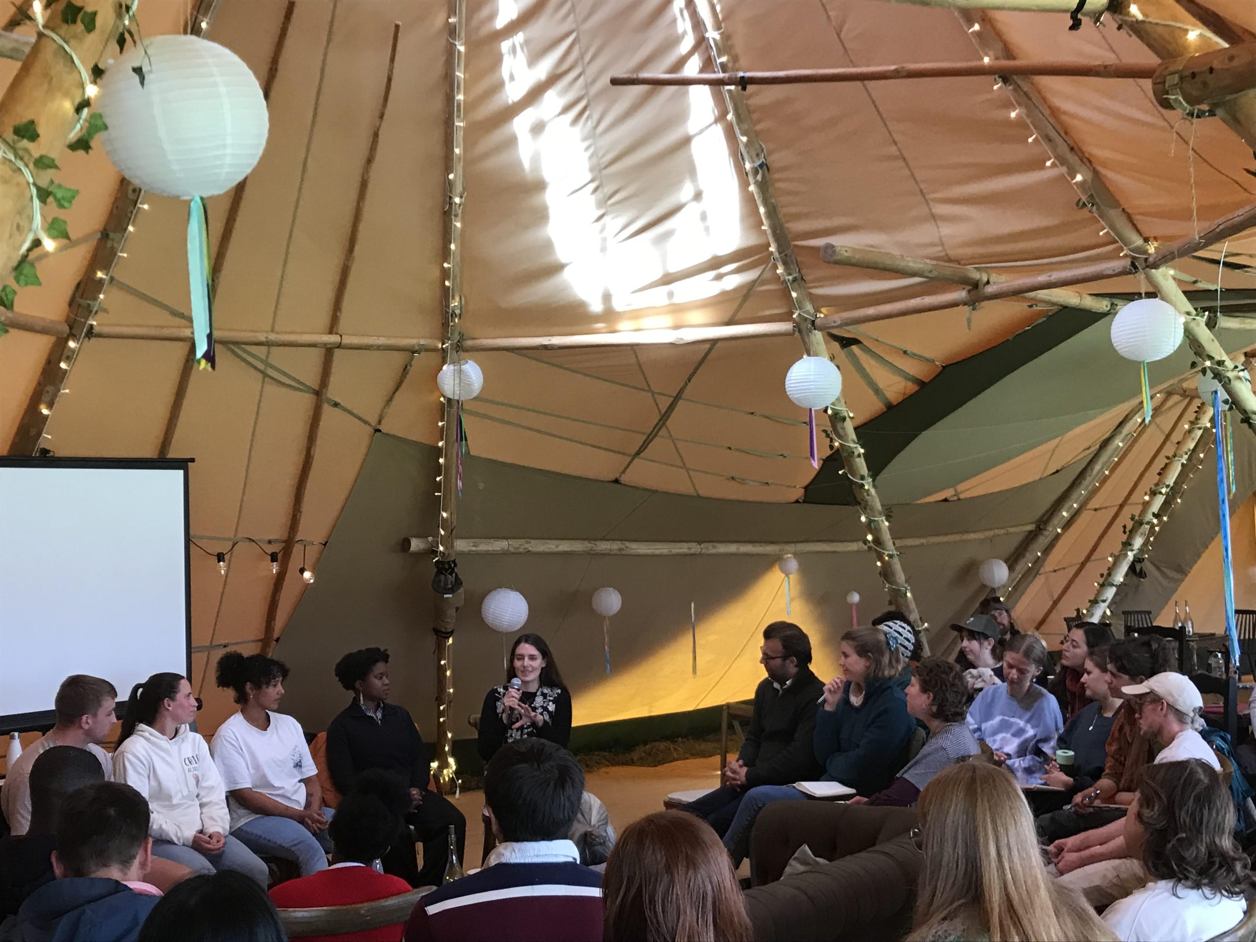 Event attendees listen to a panel talk in a tent 